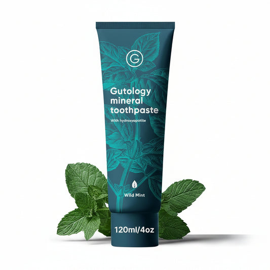Gutology mineral toothpaste tube with mint leaves on a white background